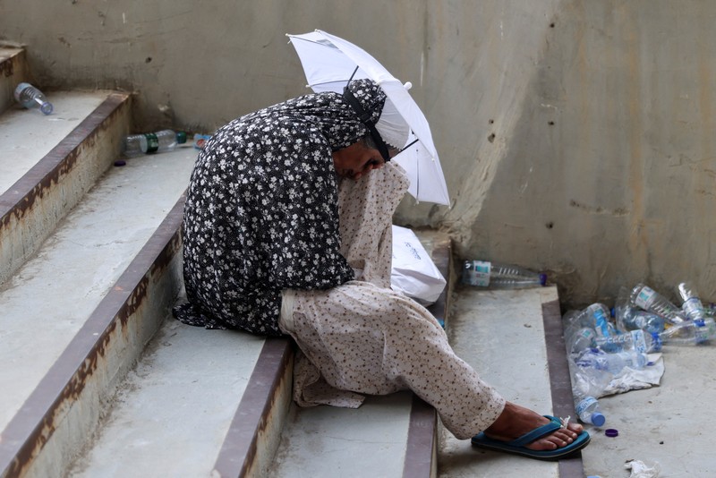Two muslim pilgrim women share umbrella to protect themself from sun near pillars in the symbolic stoning of the devil, the last rite of the annual hajj, in Mina, near the holy city of Mecca, Saudi Arabia, Sunday, June 16, 2024. Masses of pilgrims on Sunday embarked on a symbolic stoning of the devil in Saudi Arabia. The ritual marks the final days of the Hajj, or Islamic pilgrimage, and the start of the Eid al-Adha celebrations for Muslims around the world. (AP Photo/Rafiq Maqbool)