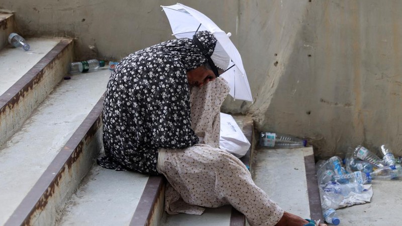 Two muslim pilgrim women share umbrella to protect themself from sun near pillars in the symbolic stoning of the devil, the last rite of the annual hajj, in Mina, near the holy city of Mecca, Saudi Arabia, Sunday, June 16, 2024. Masses of pilgrims on Sunday embarked on a symbolic stoning of the devil in Saudi Arabia. The ritual marks the final days of the Hajj, or Islamic pilgrimage, and the start of the Eid al-Adha celebrations for Muslims around the world. (AP Photo/Rafiq Maqbool)
