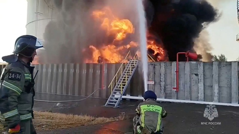 Anggota kementerian darurat Rusia bekerja untuk memadamkan api di tangki penyimpanan minyak setelah dugaan serangan pesawat tak berawak di kota Azov di wilayah selatan Rostov, Rusia, 18 Juni 2024. (Russian Emergencies Ministry/Handout via REUTERS)