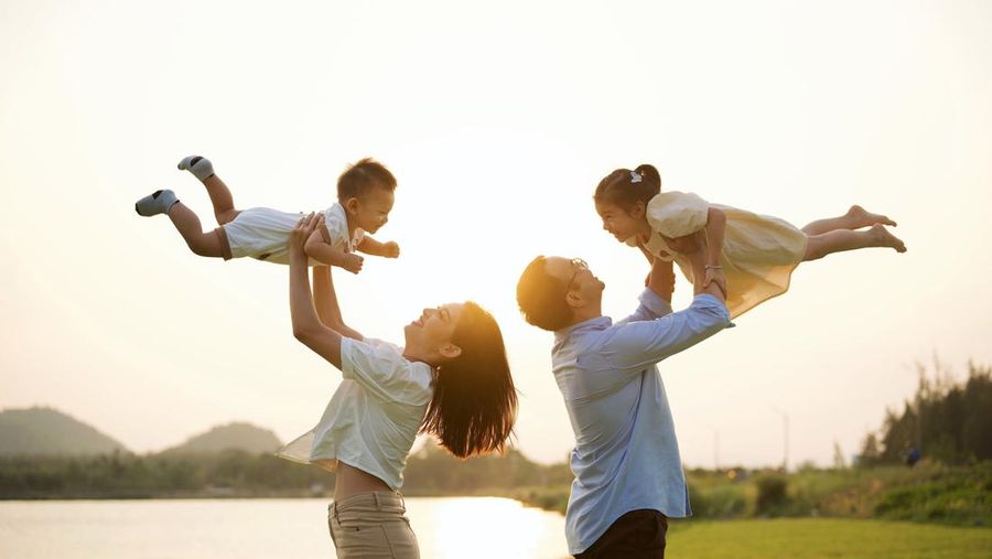 Portrait of happy family travel in park on weekend with sunset view, Father mother and children having activities outdoor playing together with happiness, Family lifestyle