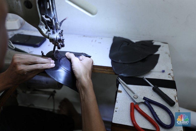Pekerja menyelesaikan pembuatan pola alas kaki sepatu kulit di workshop Flavio Boston di kawasan Jakarta, Rabu (19/6/2024). (CNBC Indonesia/Tri Susilo)