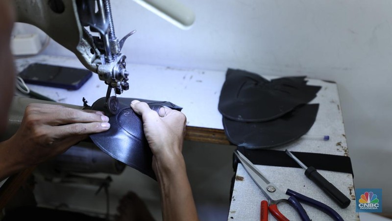 Pekerja menyelesaikan pembuatan pola alas kaki sepatu kulit di workshop Flavio Boston di kawasan Jakarta, Rabu (19/6/2024). (CNBC Indonesia/Tri Susilo)