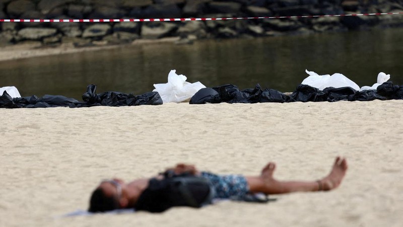 Pembersihan tumpahan minyak di Pantai Tanjong, Sentosa, Singapura, Selasa (18/6/2024). (REUTERS/Edgar Su)