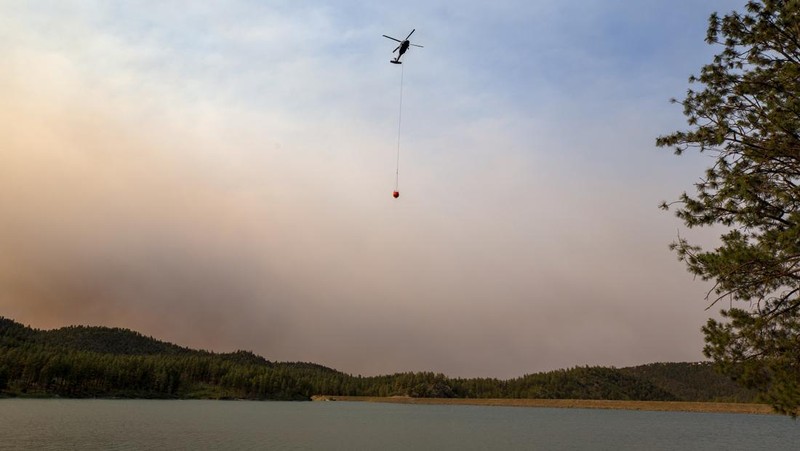 Sebuah helikopter mengambil air dari danau Mescalero saat terjadi kebakaran hutan di New Mexico, Amerika Serikat (AS), Selasa (18/6/2024).  (AP Photo/Andres Leighton)