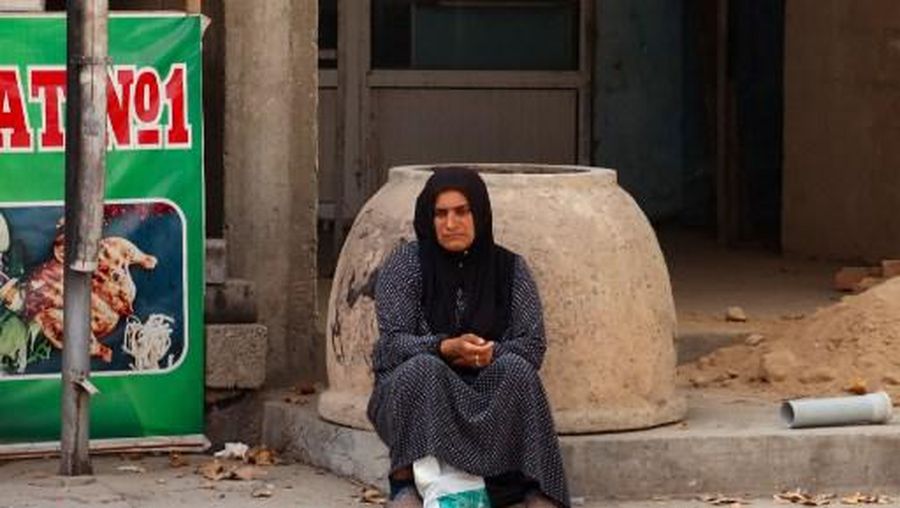 A woman sits on a street in the city of Vakhdat, some 21 km east of the Tajik capital Dushanbe, on September 16, 2023. (Photo by Nasim ISAMOV / AFP)