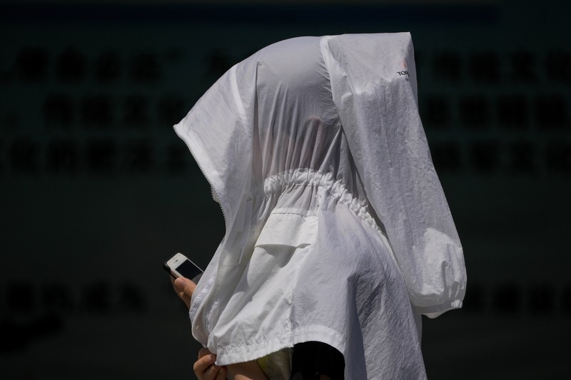 Warga Beijing menggunakan pelindung wajah saat beraktivitas diluar rumah di tengah cuaca panas ekstrem. (AP Photo/Andy Wong) Warga Beijing menggunakan pelindung wajah saat beraktivitas diluar rumah di tengah cuaca panas ekstrem. (AP Photo/Andy Wong)