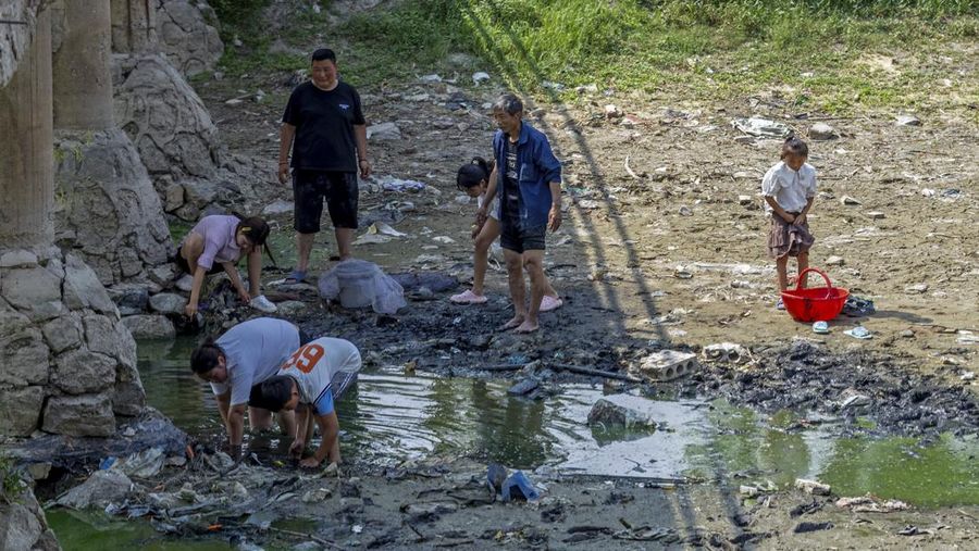 Warga Beijing menggunakan pelindung wajah saat beraktivitas diluar rumah di tengah cuaca panas ekstrem. (AP Photo/Andy Wong)