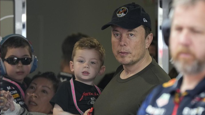 Elon Musk menggendong salah satu anaknya saat dia menyaksikan kru Red Bull mempersiapkan mobil pembalap Red Bull Sergio Perez dari Meksiko untuk berangkat ke trek, pada sesi latihan ketiga balapan mobil Formula Satu Grand Prix Miami, di Miami International Autodrome di Miami Gardens, Florida, Sabtu, 6 Mei 2023. (AP Photo/Rebecca Blackwell/File Foto)