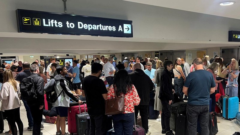Penumpang mengantri di luar Terminal 1 setelah pemadaman listrik semalaman menyebabkan gangguan dan pembatalan di Bandara Manchester di Manchester, Inggris, 23 Juni 2024. (REUTERS/Phil Noble)