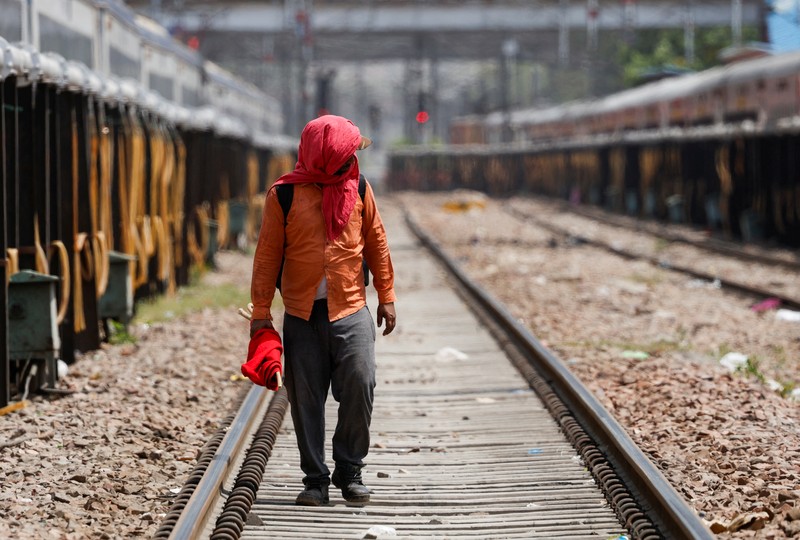 Seorang pria menutupi wajahnya menggunakan kain untuk melindungi dirinya dari sinar matahari saat dia memeriksa rel kereta api pada hari musim panas di New Delhi, India, 18 Juni 2024. (REUTERS/Priyanshu Singh)