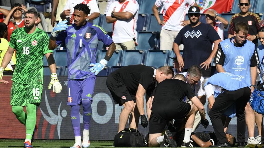 Kiper Kanada Maxime Crepeau, rekan setimnya Liam Millar, kanan, dan wasit Mario Escobar, dari Guatemala, merawat asisten wasit Humberto Panjoj setelah ia pingsan saat pertandingan sepak bola Grup A Copa America di Kansas City, Kansas, Selasa, 25 Juni 2024 . (AP Photo/Ed Zurga)