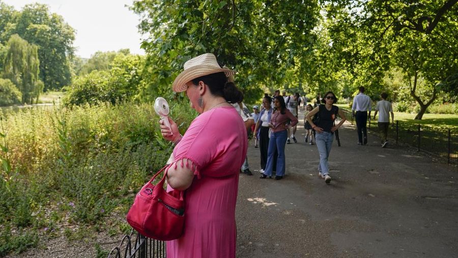 A woman holds a portable fan in St James's park, in London, Tuesday, June 25, 2024, as the temperatures are set to reach 28C during the week. (AP Photo/Alberto Pezzali)