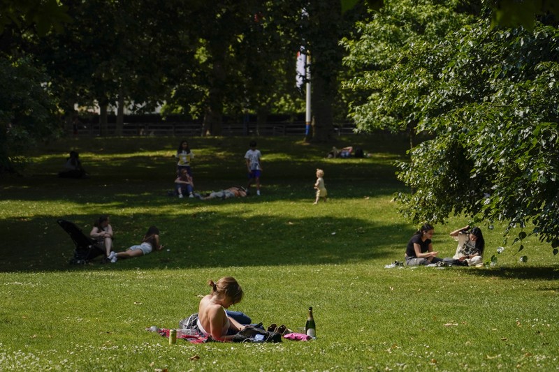 A woman holds a portable fan in St James's park, in London, Tuesday, June 25, 2024, as the temperatures are set to reach 28C during the week. (AP Photo/Alberto Pezzali)