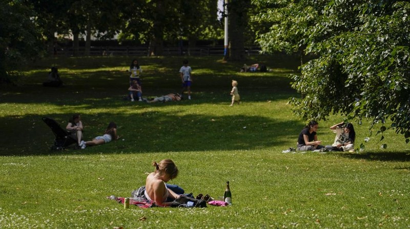 A woman holds a portable fan in St James's park, in London, Tuesday, June 25, 2024, as the temperatures are set to reach 28C during the week. (AP Photo/Alberto Pezzali)