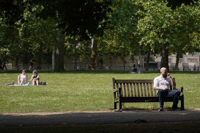 A woman holds a portable fan in St James's park, in London, Tuesday, June 25, 2024, as the temperatures are set to reach 28C during the week. (AP Photo/Alberto Pezzali)