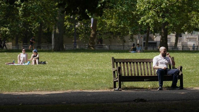A woman holds a portable fan in St James's park, in London, Tuesday, June 25, 2024, as the temperatures are set to reach 28C during the week. (AP Photo/Alberto Pezzali)