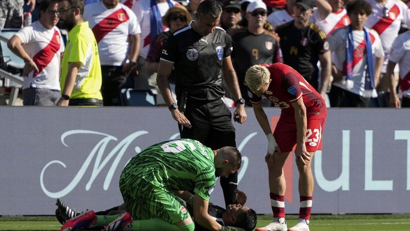 Kiper Kanada Maxime Crepeau, rekan setimnya Liam Millar, kanan, dan wasit Mario Escobar, dari Guatemala, merawat asisten wasit Humberto Panjoj setelah ia pingsan saat pertandingan sepak bola Grup A Copa America di Kansas City, Kansas, Selasa, 25 Juni 2024 . (AP Photo/Ed Zurga)