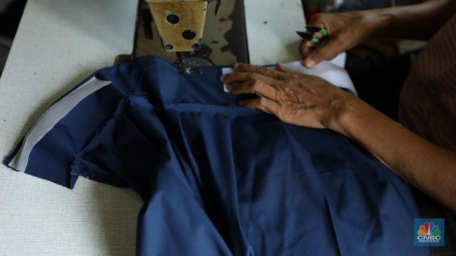 Penjahit menyelesaikan pembuatan baju seragam sekolah di sebuah industri rumahan di kawasan Jakarta, Rabu (26/6/2024).  (CNBC Indonesia/Tri Susilo)
