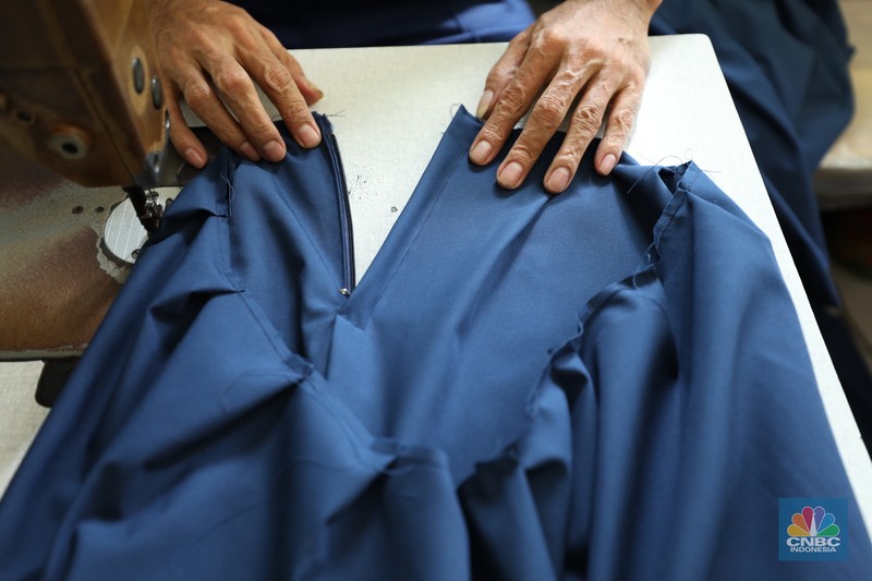 Penjahit menyelesaikan pembuatan baju seragam sekolah di sebuah industri rumahan di kawasan Jakarta, Rabu (26/6/2024).  (CNBC Indonesia/Tri Susilo)