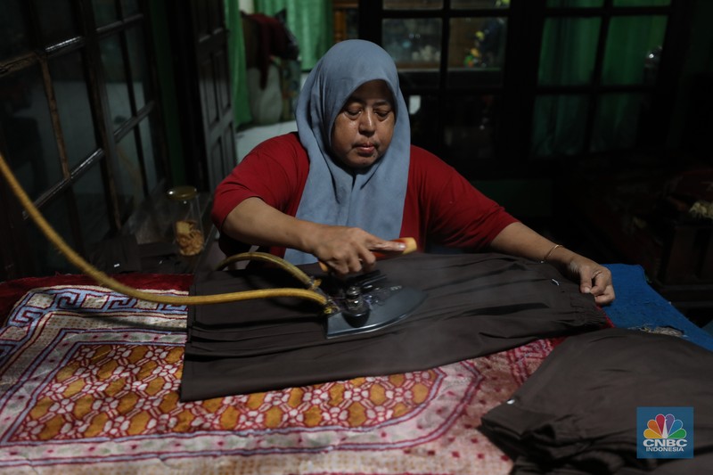 Penjahit menyelesaikan pembuatan baju seragam sekolah di sebuah industri rumahan di kawasan Jakarta, Rabu (26/6/2024).  (CNBC Indonesia/Tri Susilo)