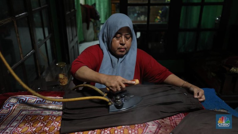 Penjahit menyelesaikan pembuatan baju seragam sekolah di sebuah industri rumahan di kawasan Jakarta, Rabu (26/6/2024).  (CNBC Indonesia/Tri Susilo)