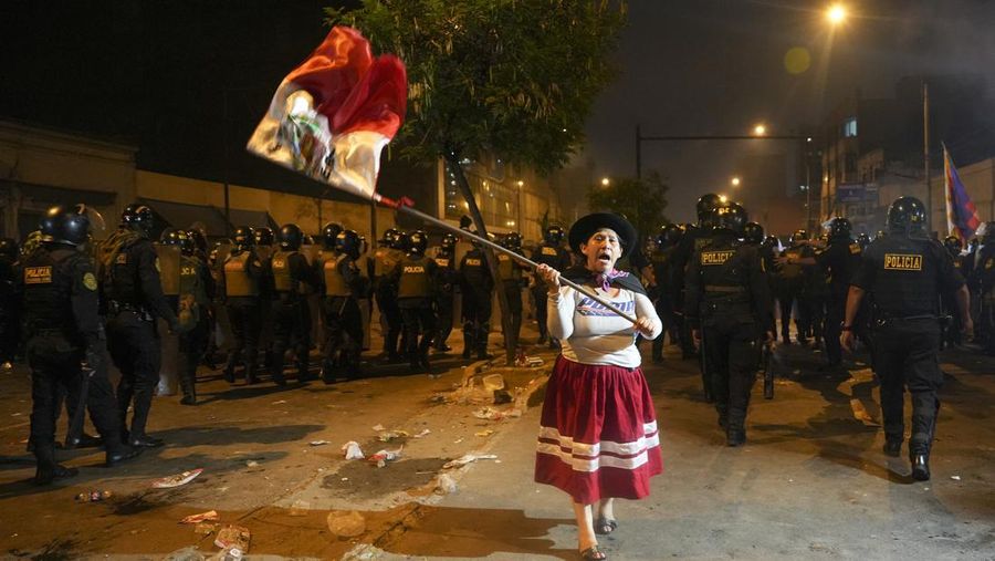 Seorang wanita mengibarkan bendera Peru saat protes anti-pemerintah di Lima, Peru, Jumat, 20 Januari 2023. Para pengunjuk rasa menuntut pengunduran diri Presiden Dina Boluarte, pembebasan Presiden terguling Pedro Castillo dari penjara, dan pemilihan umum segera. (Foto AP/Guadalupe Pardo)
