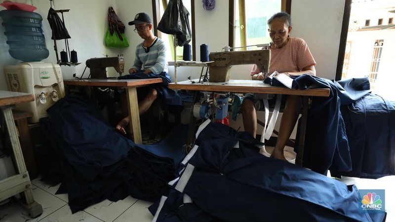 Penjahit menyelesaikan pembuatan baju seragam sekolah di sebuah industri rumahan di kawasan Jakarta, Rabu (26/6/2024).  (CNBC Indonesia/Tri Susilo)