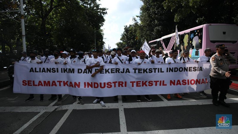Ratusan buruh tekstil melakukan longmarch dari IRTI menuju Patung Kuda Jakarta, Kamis (27/6/2024). Massa yang tergabung dalam aliansi IKM & Pekerja Tekstil Indonesia menuntut tanggung jawab atas badai pemutusan hubungan kerja (PHK) di sejumlah industri tekstil dan produk tekstil (TPT) yang marak belakangan ini. (CNBC Indonesia/Tri Susilo)
