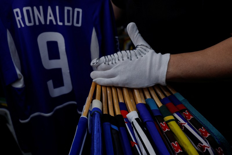 Cassio Brandao, 41, holds a shirt worn by Pele during a match with the presence of Britain's Queen Elizabeth in 1968, in a room filled with clothes racks that in April 2024 made him become a Guinness World Records title holder, as the owner of the world's largest collection of soccer shirts, in Sao Paulo, Brazil June 24, 2024. REUTERS/Amanda Perobelli