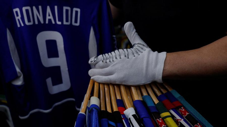 Cassio Brandao, 41, holds a shirt worn by Pele during a match with the presence of Britain's Queen Elizabeth in 1968, in a room filled with clothes racks that in April 2024 made him become a Guinness World Records title holder, as the owner of the world's largest collection of soccer shirts, in Sao Paulo, Brazil June 24, 2024. REUTERS/Amanda Perobelli