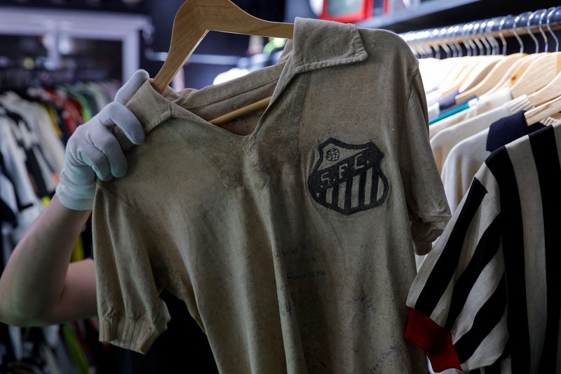 Cassio Brandao, 41, holds a shirt worn by Pele during a match with the presence of Britain's Queen Elizabeth in 1968, in a room filled with clothes racks that in April 2024 made him become a Guinness World Records title holder, as the owner of the world's largest collection of soccer shirts, in Sao Paulo, Brazil June 24, 2024. REUTERS/Amanda Perobelli