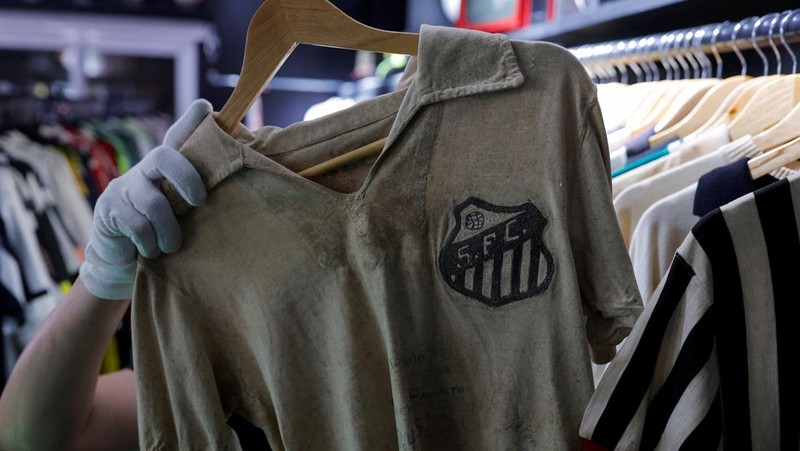Cassio Brandao, 41, holds a shirt worn by Pele during a match with the presence of Britain's Queen Elizabeth in 1968, in a room filled with clothes racks that in April 2024 made him become a Guinness World Records title holder, as the owner of the world's largest collection of soccer shirts, in Sao Paulo, Brazil June 24, 2024. REUTERS/Amanda Perobelli