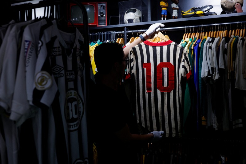 Cassio Brandao, 41, holds a shirt worn by Pele during a match with the presence of Britain's Queen Elizabeth in 1968, in a room filled with clothes racks that in April 2024 made him become a Guinness World Records title holder, as the owner of the world's largest collection of soccer shirts, in Sao Paulo, Brazil June 24, 2024. REUTERS/Amanda Perobelli