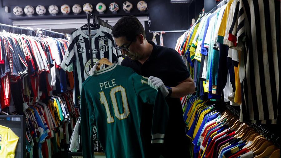Cassio Brandao, 41, holds a shirt worn by Pele during a match with the presence of Britain's Queen Elizabeth in 1968, in a room filled with clothes racks that in April 2024 made him become a Guinness World Records title holder, as the owner of the world's largest collection of soccer shirts, in Sao Paulo, Brazil June 24, 2024. REUTERS/Amanda Perobelli