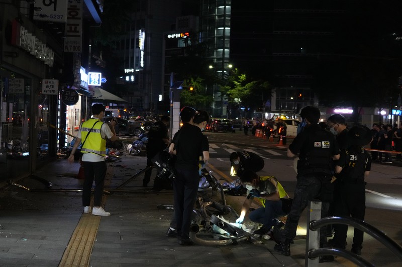 Polisi dan tim penyelamat berdiri di samping mobil yang terlibat dalam kecelakaan yang mengakibatkan beberapa orang tewas dan terluka di pusat kota Seoul, Korea Selatan 1 Juli 2024. (REUTERS/Kim Hong-Ji)