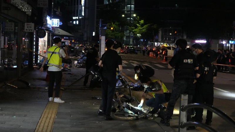 Polisi dan tim penyelamat berdiri di samping mobil yang terlibat dalam kecelakaan yang mengakibatkan beberapa orang tewas dan terluka di pusat kota Seoul, Korea Selatan 1 Juli 2024. (REUTERS/Kim Hong-Ji)