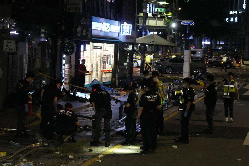 Polisi dan tim penyelamat berdiri di samping mobil yang terlibat dalam kecelakaan yang mengakibatkan beberapa orang tewas dan terluka di pusat kota Seoul, Korea Selatan 1 Juli 2024. (REUTERS/Kim Hong-Ji)