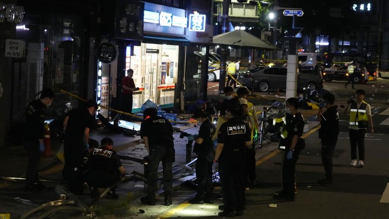 Polisi dan tim penyelamat berdiri di samping mobil yang terlibat dalam kecelakaan yang mengakibatkan beberapa orang tewas dan terluka di pusat kota Seoul, Korea Selatan 1 Juli 2024. (REUTERS/Kim Hong-Ji)