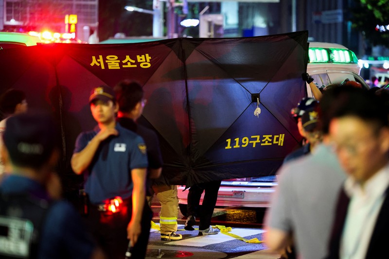 Polisi dan tim penyelamat berdiri di samping mobil yang terlibat dalam kecelakaan yang mengakibatkan beberapa orang tewas dan terluka di pusat kota Seoul, Korea Selatan 1 Juli 2024. (REUTERS/Kim Hong-Ji)