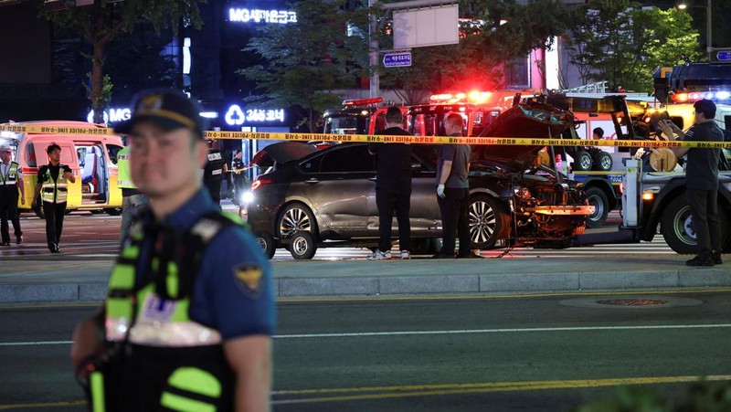 Polisi dan tim penyelamat berdiri di samping mobil yang terlibat dalam kecelakaan yang mengakibatkan beberapa orang tewas dan terluka di pusat kota Seoul, Korea Selatan 1 Juli 2024. (REUTERS/Kim Hong-Ji)