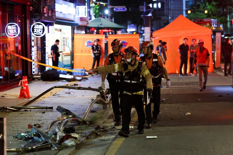 Polisi dan tim penyelamat berdiri di samping mobil yang terlibat dalam kecelakaan yang mengakibatkan beberapa orang tewas dan terluka di pusat kota Seoul, Korea Selatan 1 Juli 2024. (REUTERS/Kim Hong-Ji)