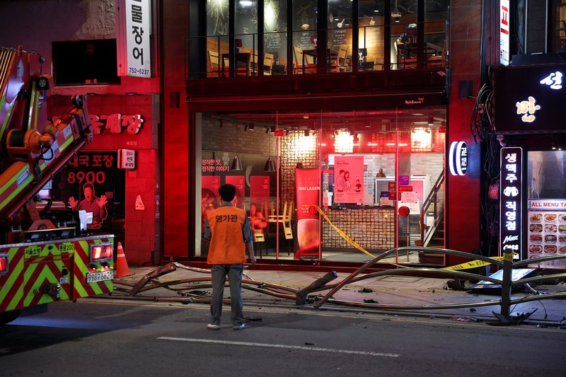 Polisi dan tim penyelamat berdiri di samping mobil yang terlibat dalam kecelakaan yang mengakibatkan beberapa orang tewas dan terluka di pusat kota Seoul, Korea Selatan 1 Juli 2024. (REUTERS/Kim Hong-Ji)