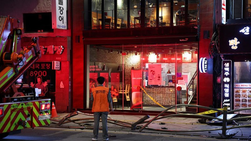 Polisi dan tim penyelamat berdiri di samping mobil yang terlibat dalam kecelakaan yang mengakibatkan beberapa orang tewas dan terluka di pusat kota Seoul, Korea Selatan 1 Juli 2024. (REUTERS/Kim Hong-Ji)