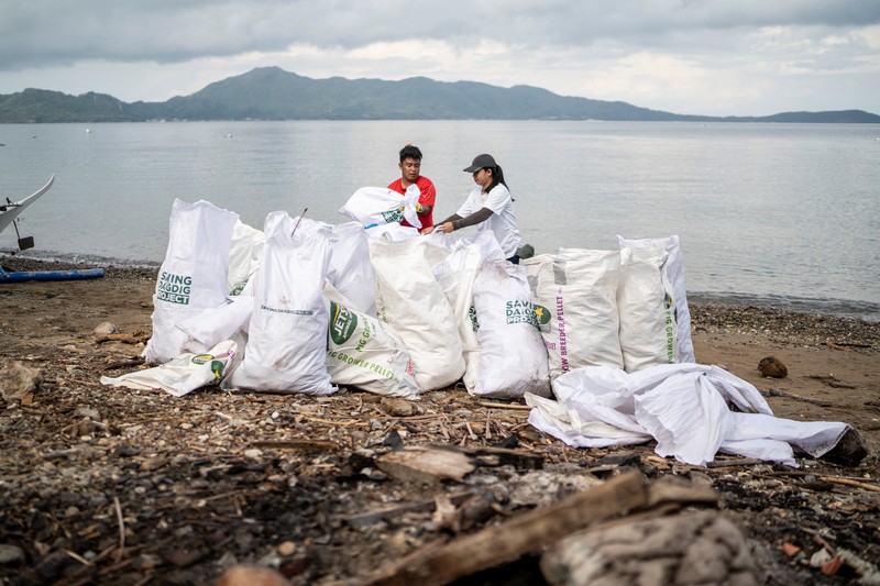 Orang-orang mengumpulkan sampah plastik di pantai saat program pembersihan pantai yang menyediakan beras kepada relawan sebagai imbalan atas sampah plastik, di Mabini, provinsi Batangas, Filipina, 15 Juni 2024. Orang-orang mengumpulkan sampah plastik di pantai saat program pembersihan pantai yang menyediakan beras kepada relawan sebagai imbalan atas sampah plastik, di Mabini, provinsi Batangas, Filipina, 15 Juni 2024. (REUTERS/Lisa Marie David)