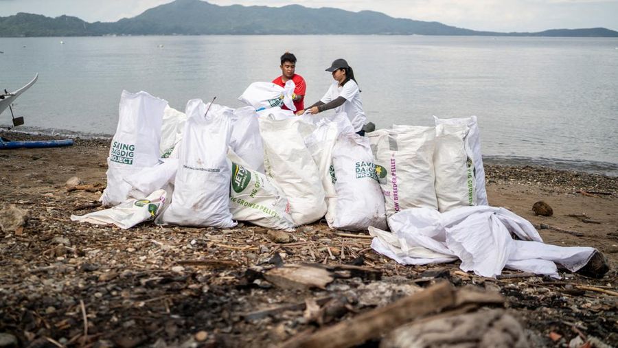 Orang-orang mengumpulkan sampah plastik di pantai saat program pembersihan pantai yang menyediakan beras kepada relawan sebagai imbalan atas sampah plastik, di Mabini, provinsi Batangas, Filipina, 15 Juni 2024. (REUTERS/Lisa Marie David)