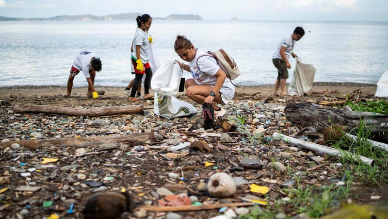 Orang-orang mengumpulkan sampah plastik di pantai saat program pembersihan pantai yang menyediakan beras kepada relawan sebagai imbalan atas sampah plastik, di Mabini, provinsi Batangas, Filipina, 15 Juni 2024. (REUTERS/Lisa Marie David)