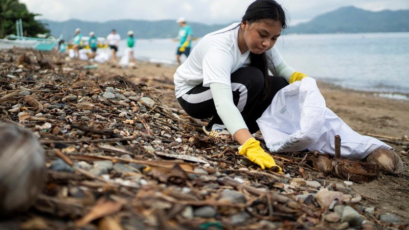 Orang-orang mengumpulkan sampah plastik di pantai saat program pembersihan pantai yang menyediakan beras kepada relawan sebagai imbalan atas sampah plastik, di Mabini, provinsi Batangas, Filipina, 15 Juni 2024. (REUTERS/Lisa Marie David)