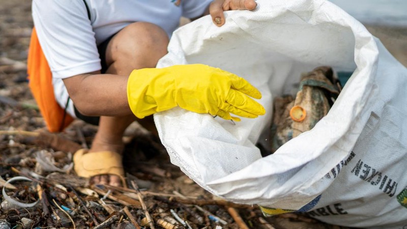 Orang-orang mengumpulkan sampah plastik di pantai saat program pembersihan pantai yang menyediakan beras kepada relawan sebagai imbalan atas sampah plastik, di Mabini, provinsi Batangas, Filipina, 15 Juni 2024. (REUTERS/Lisa Marie David)