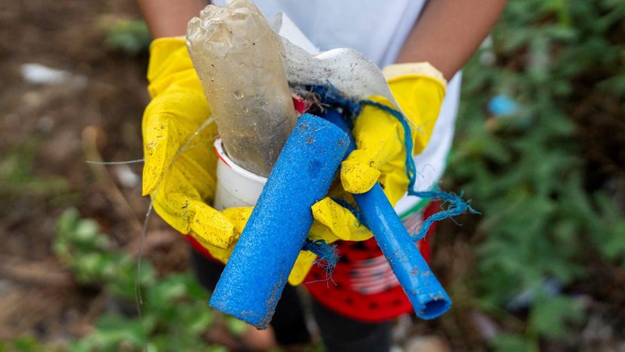 Seorang wanita menunjukkan sampah plastik yang dikumpulkan di pantai selama program pembersihan pantai yang menyediakan beras kepada relawan sebagai imbalan atas sampah plastik, di Mabini, provinsi Batangas, Filipina, 15 Juni 2024. (REUTERS/Lisa Marie David)