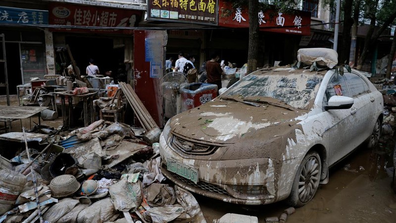 Sebuah mobil dan tumpukan puing-puing terlihat di jalan setelah banjir menyusul hujan lebat di daerah Pingjiang, Yueyang, provinsi Hunan, Tiongkok 3 Juli 2024. (REUTERS/Tingshu Wang)